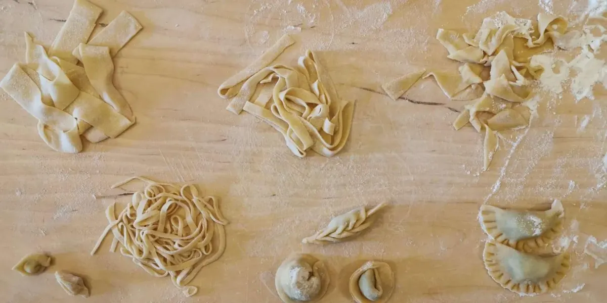 Different handmade pasta shapes laid out on a floured worktop